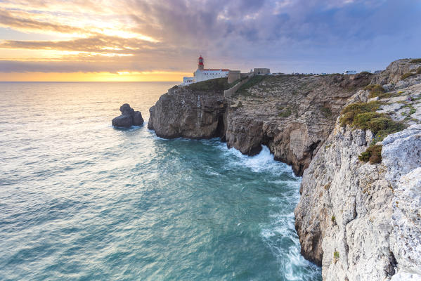 The cliffs and lighthouse of Cabo De San Vicente at sunset, overlooking the Atlantic Ocean. Sagres, Vila do Bispo, Algarve, Portugal, Europe.