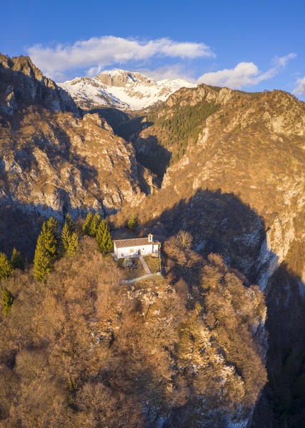 Aerial view of the small church called San Peder and the Presolana during a winter sunset. Rusio, Castione della Presolana, Val Seriana, Bergamo district, Lombardy, Italy.