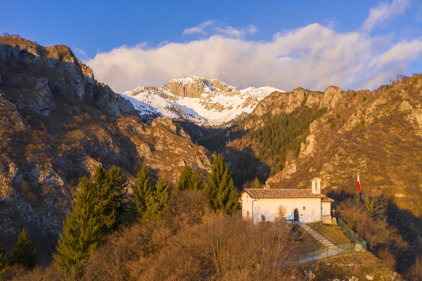 Aerial view of the small church called San Peder and the Presolana during a winter sunset. Rusio, Castione della Presolana, Val Seriana, Bergamo district, Lombardy, Italy.