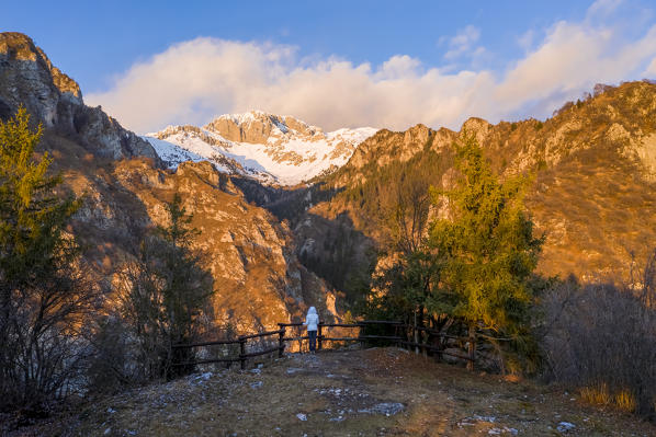 A person admiring the Presolana during a winter sunset from the balcony of the small church called San Peder. Rusio, Castione della Presolana, Val Seriana, Bergamo district, Lombardy, Italy.