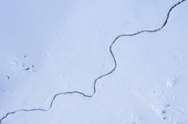 Aerial view of an iced river at the Campelli di Schilpario covered in snow in winter. Schilpario, Val di Scalve, Bergamo district, Lombardy, Italy, Southern Europe.