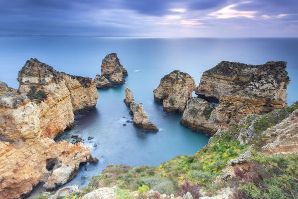 Cloudy sunrise at the yellow and red cliffs of Ponta da Piedade. Lagos, Algarve, Portugal, Europe.