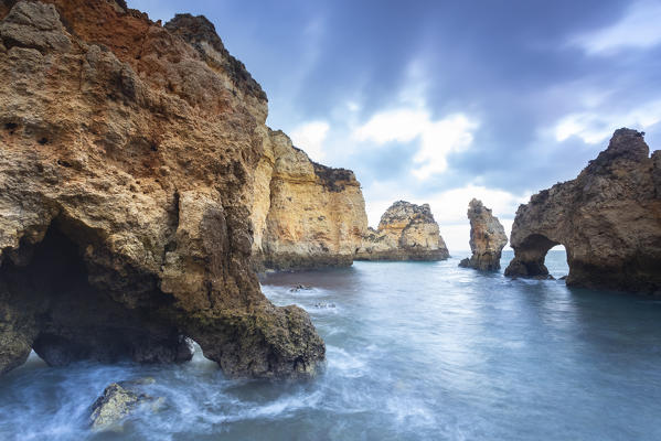 Cloudy sunrise at the yellow and red cliffs of Ponta da Piedade. Lagos, Algarve, Portugal, Europe.