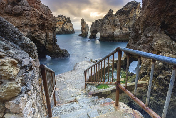 Banisters leading to the bottom of Ponta da Piedade during a cloudy sunrise. Lagos, Algarve, Portugal, Europe.