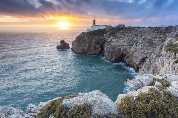 The cliffs and lighthouse of Cabo De San Vicente at sunset, overlooking the Atlantic Ocean. Sagres, Vila do Bispo, Algarve, Portugal, Europe.