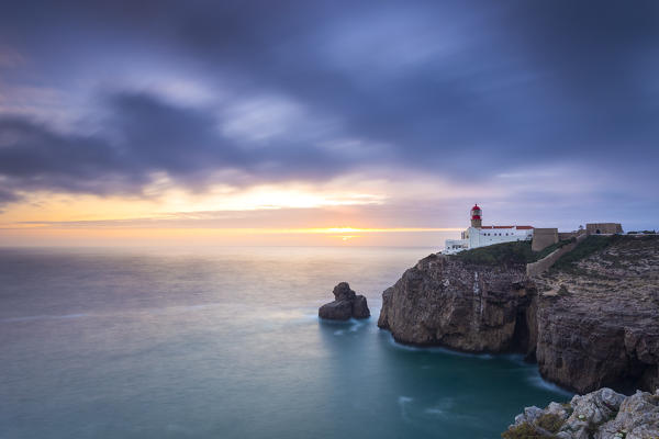 The cliffs and lighthouse of Cabo De San Vicente at sunset, overlooking the Atlantic Ocean. Sagres, Vila do Bispo, Algarve, Portugal, Europe.