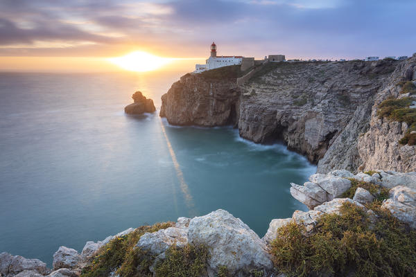 The cliffs and lighthouse of Cabo De San Vicente at sunset, overlooking the Atlantic Ocean. Sagres, Vila do Bispo, Algarve, Portugal, Europe.