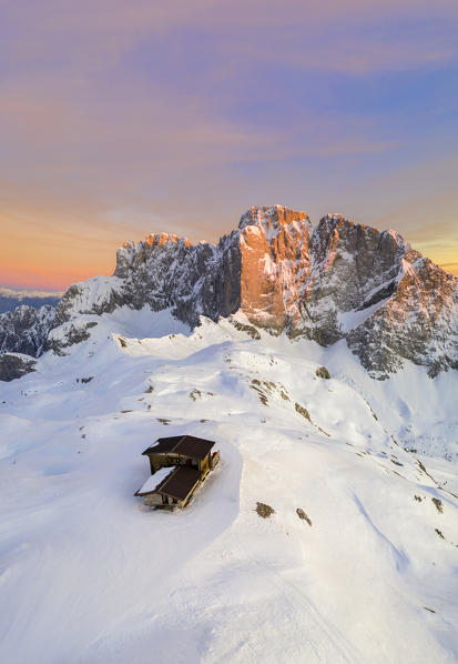 Aerial view of the snow-covered north face of the Presolana mountain and the Rifugio Aquila in winter at sunset. Val di Scalve, Bergamo district, Lombardy, Italy, Southern Europe.