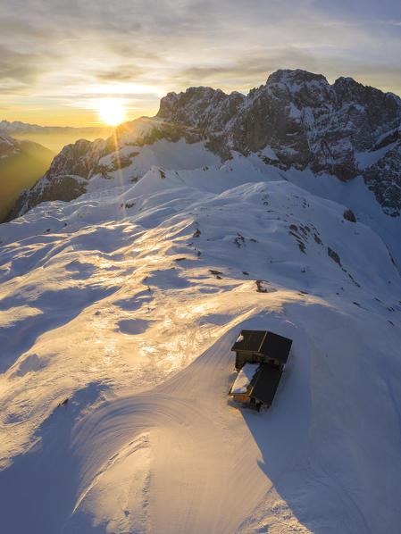 Aerial view of the snow-covered north face of the Presolana mountain and the Rifugio Aquila in winter at sunrise. Val di Scalve, Bergamo district, Lombardy, Italy, Southern Europe.