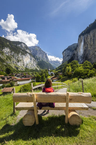 A tourist admire the Lauterbrunnen village from the famous bench. Lauterbrunnen, Canton of Bern, Switzerland, Europe.
