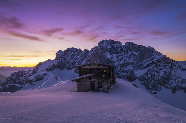 View of the snow-covered north face of the Presolana mountain in winter at sunrise with the Aquila refuge. Colere, Val di Scalve, Bergamo district, Lombardy, Italy, Southern Europe.