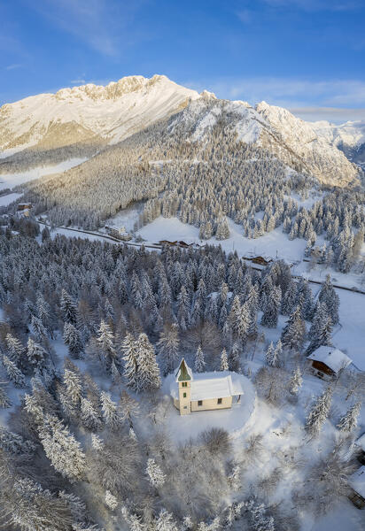 Aerial view of the Silvestri church and the Presolana massif after a winter sunrise. Presolana pass, Castione della Presolana, Seriana Valley, Bergamo province, Lombardy, Italy.