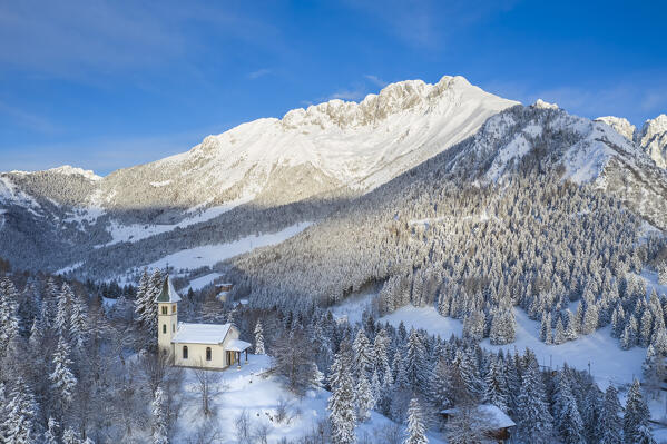 Aerial view of the Silvestri church and the Presolana massif after a winter sunrise. Presolana pass, Castione della Presolana, Seriana Valley, Bergamo province, Lombardy, Italy.