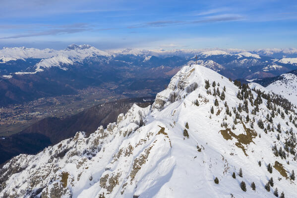 Aerial view of the iron cross on top of Pizzo Formico with Val Seriana and Presolana in the background in winter. Monte Farno, Gandino, Valgandino, Val Seriana, Bergamo province, Lombardy, Italy.