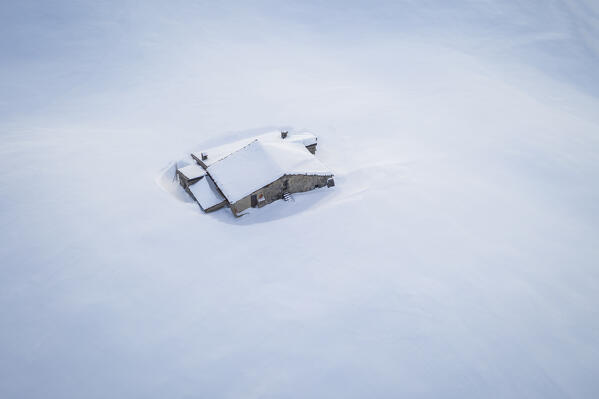 Aerial view of a mountain hut covered in snow at Monte Farno. Monte Farno, Gandino, Valgandino, Val Seriana, Bergamo province, Lombardy, Italy.