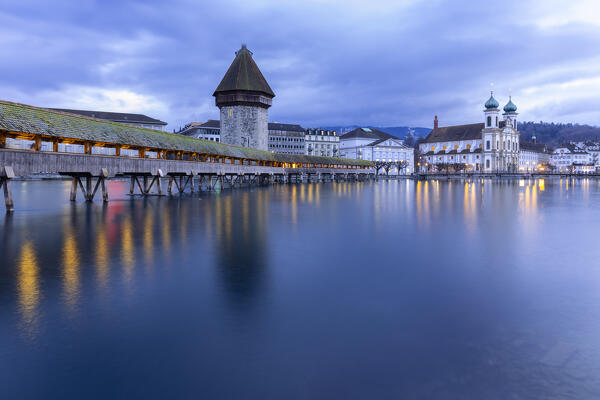 View of the Kapellbrücke bridge, the Jesuit Church and the  Wasserturm at blue hour reflected on the Reuss river. Lucerne, canton of Lucerne, Switzerland.