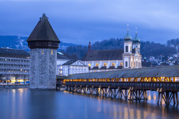 View of the Kapellbrücke bridge, the Jesuit Church and the  Wasserturm at blue hour reflected on the Reuss river. Lucerne, canton of Lucerne, Switzerland.
