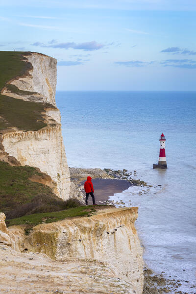 A person looking towards Beachy Head lighthouse from the chalk headland. Eastbourne, East Sussex, Southern England.