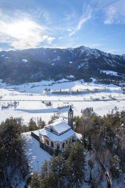 Aerial view of the fields surrounding the small church of Chiesa della Santissima Trinità in Clusone city in winter. Val Seriana, Bergamo district, Lombardy, Italy.