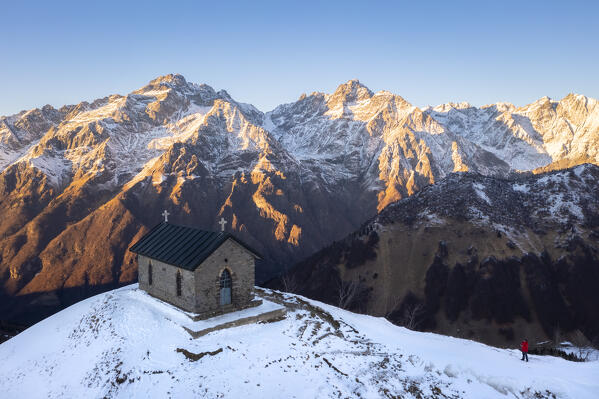 Aerial view of the small church at the top of the Manina Pass, between Scalve Valley and Seriana Valley at sunset in winter. Nona, Vilminore di Scalve, Scalve Valley, Lombardy, Bergamo province, Italy.
