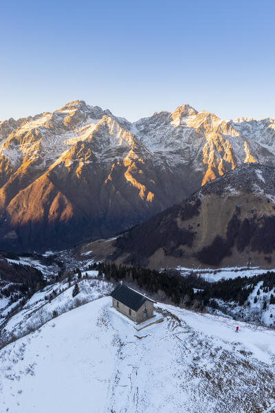 Aerial view of the small church at the top of the Manina Pass, between Scalve Valley and Seriana Valley at sunset in winter. Nona, Vilminore di Scalve, Scalve Valley, Lombardy, Bergamo province, Italy.