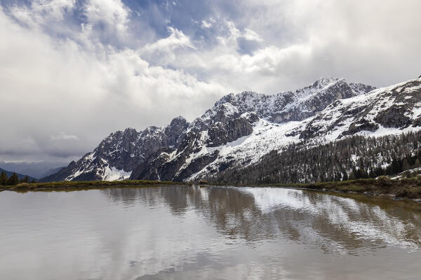 Reflection of the north face of the Presolana mountain in a spring pond. Colere, Val di Scalve, Bergamo district, Lombardy, Italy, Southern Europe.