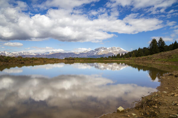 View of the Presolana mountain reflected on a spring pond on Monte Pora. Songavazzo, Val Seriana, Bergamo district, Lombardy, Italy, Southern Europe.