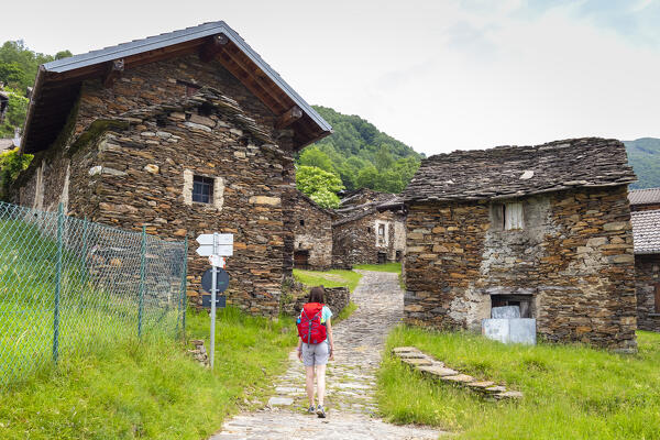View of a person walking in the small village of Sarona, Curiglia con Monteviasco, Veddasca valley, Varese district, Lombardy, Italy.