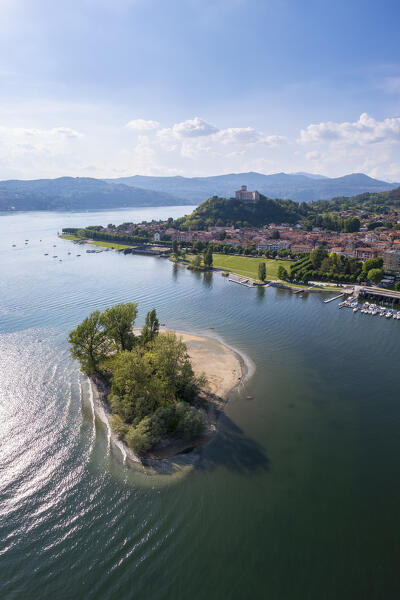 View of the town of Angera and its fortress called Rocca di Angera on a spring day with the small island called Isolino Partegora. Angera, Lake Maggiore, Varese district, Lombardy, Italy.