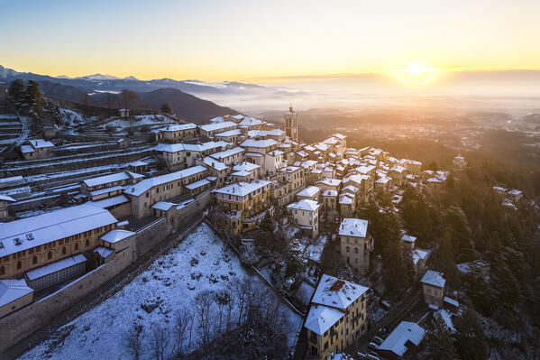 Aerial view of the town of Santa Maria del Monte after a snowfall in winter at sunrise. Varese, Parco Campo dei Fiori, Lombardy, Italy.