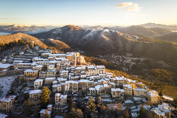 Aerial view of the town of Santa Maria del Monte after a snowfall in winter at sunrise. Varese, Parco Campo dei Fiori, Lombardy, Italy.