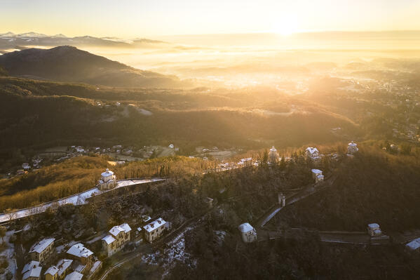 Aerial view of the chapels of Sacro Monte di Varese after a snowfall in winter at sunrise. Varese, Parco Campo dei Fiori, Lombardy, Italy.
