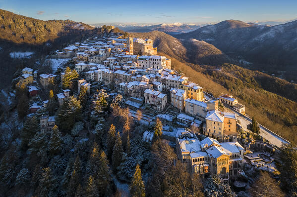 Aerial view of the town of Santa Maria del Monte after a snowfall in winter at sunrise. Varese, Parco Campo dei Fiori, Lombardy, Italy.