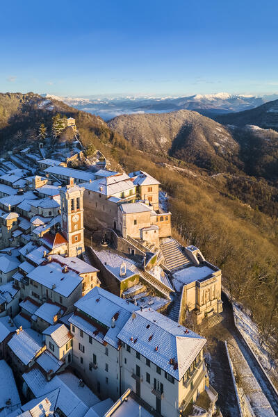 Aerial view of the town of Santa Maria del Monte after a snowfall in winter at sunrise. Varese, Parco Campo dei Fiori, Lombardy, Italy.