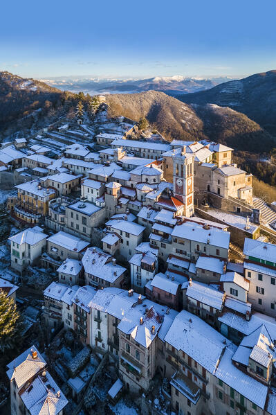 Aerial view of the town of Santa Maria del Monte after a snowfall in winter at sunrise. Varese, Parco Campo dei Fiori, Lombardy, Italy.