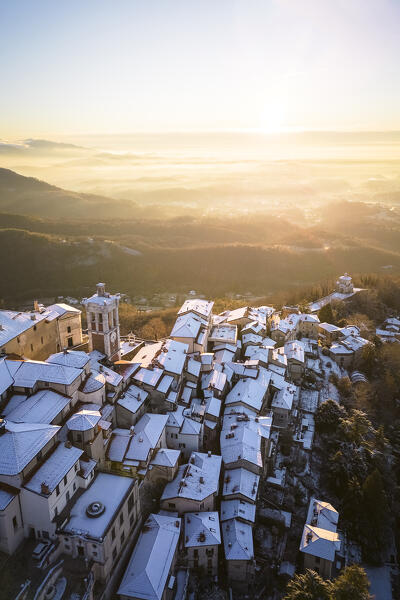 Aerial view of the town of Santa Maria del Monte after a snowfall in winter at sunrise. Varese, Parco Campo dei Fiori, Lombardy, Italy.