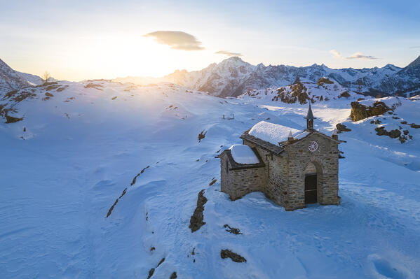 Sunset at Alpe Prabello with Santuario Madonna della Pace and Mount Disgrazia in the background in winter. Lanzada, Valmalenco, Valtellina, Sondrio district, Lombardy, Italy, Europe.