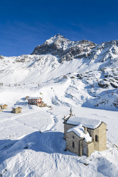 Alpe Prabello with Santuario Madonna della Pace and Mount Disgrazia in the background in winter. Lanzada, Valmalenco, Valtellina, Sondrio district, Lombardy, Italy, Europe.