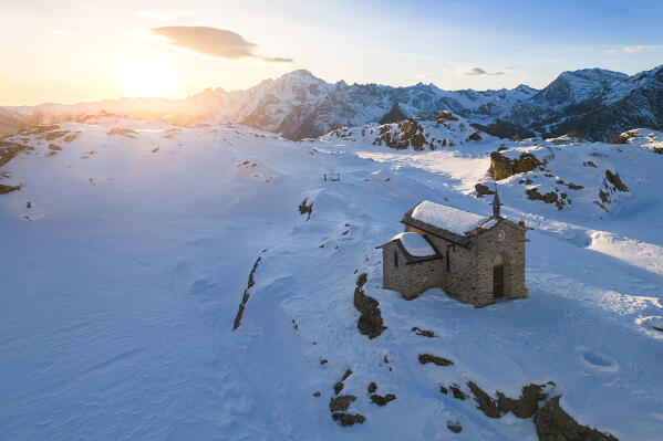 Sunset at Alpe Prabello with Santuario Madonna della Pace and Mount Disgrazia in the background in winter. Lanzada, Valmalenco, Valtellina, Sondrio district, Lombardy, Italy, Europe.