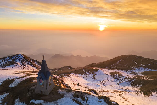 Aerial view of a winter sunset over Monumento al Redentore chapel on the top of Mount Mount Guglielmo. Zone, Brescia province, Lombardy, Italy