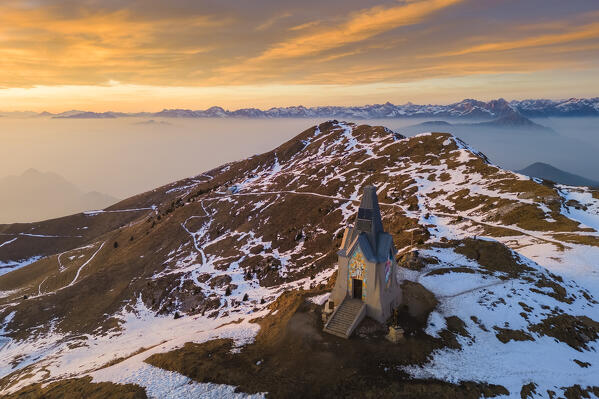 Aerial view of a winter sunset over Monumento al Redentore chapel on the top of Mount Mount Guglielmo. Zone, Brescia province, Lombardy, Italy