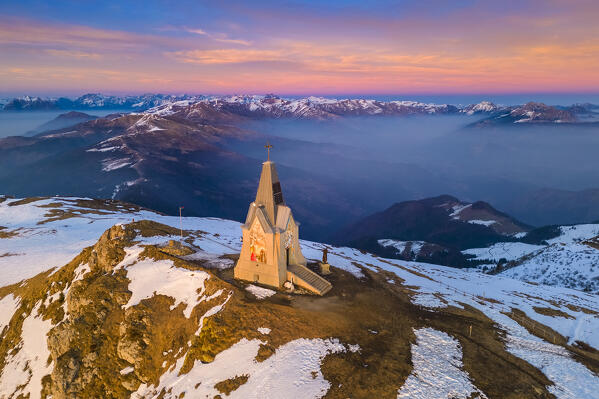 Aerial view of a winter sunset over Monumento al Redentore chapel on the top of Mount Mount Guglielmo. Zone, Brescia province, Lombardy, Italy
