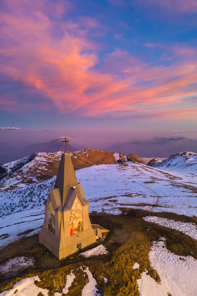 Aerial view of a winter sunset over Monumento al Redentore chapel on the top of Mount Mount Guglielmo. Zone, Brescia province, Lombardy, Italy