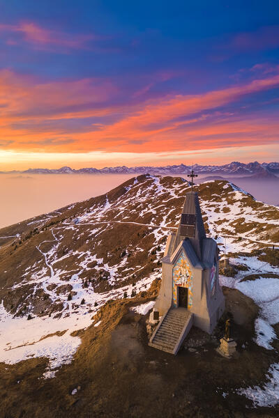 Aerial view of a winter sunset over Monumento al Redentore chapel on the top of Mount Mount Guglielmo. Zone, Brescia province, Lombardy, Italy