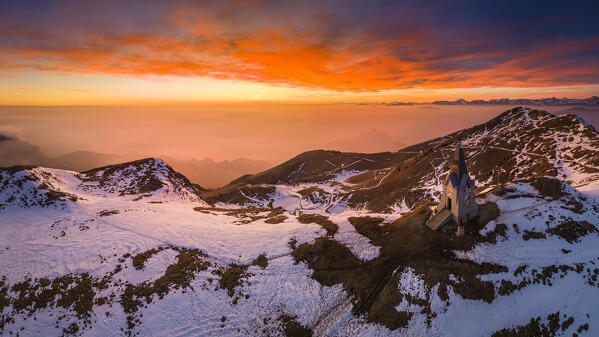 Aerial view of a winter sunset over Monumento al Redentore chapel on the top of Mount Mount Guglielmo. Zone, Brescia province, Lombardy, Italy