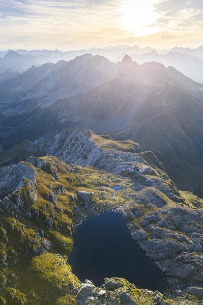 Aerial view of the Rifugio Benigni and Lago Piazzotti at sunrise. Ornica, Val Salmurano, Val Brembana, Alpi Orobie, Bergamo, Bergamo Province, Lombardy, Italy, Europe.