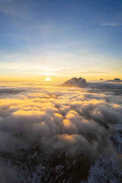 Aerial view of the Presolana mount at sunset in winter from above the clouds. Schilpario, Val di Scalve, bergamo district, Lombardy, Italy.