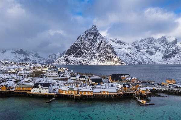 Aerial view of Olstinden mountain and Sakrisøya island in Reine Bay during winter, Lofoten Islands, Norway.