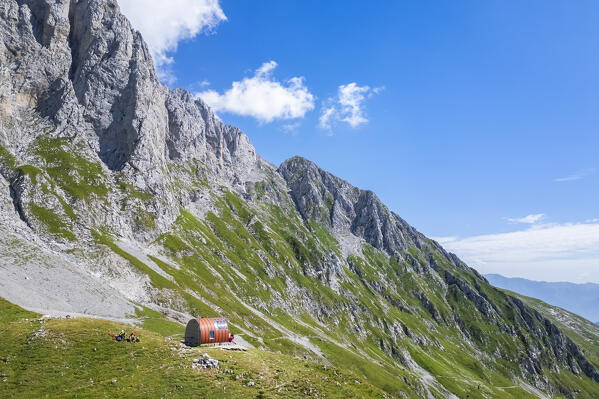 Aerial view of the Presolana covered in clouds and the Città di Clusone bivouac at it's foothills. Passo della Presolana, Castione della Presolana, Val Seriana, Bergamo district, Lombardy, Italy.