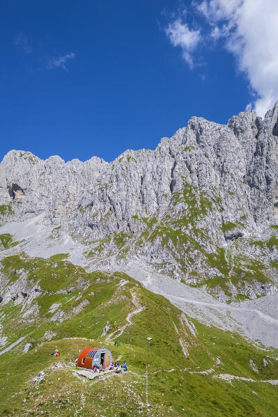 Aerial view of the Presolana covered in clouds and the Città di Clusone bivouac at it's foothills. Passo della Presolana, Castione della Presolana, Val Seriana, Bergamo district, Lombardy, Italy.
